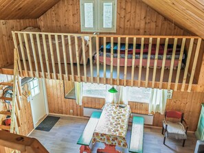 A wooden interior with a loft bed, a dining table, and a bench.