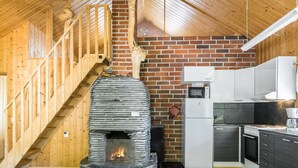 Keittiössä on kivinen takka, puinen portaikko ja modernit kodinkoneet.