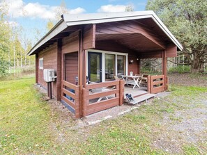 Eine Holzhütte mit überdachter Veranda, einem Tisch und Stühlen.