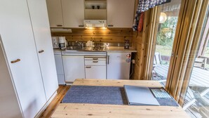 Una cocina compacta con armarios blancos, una encimera de madera y una estufa integrada.