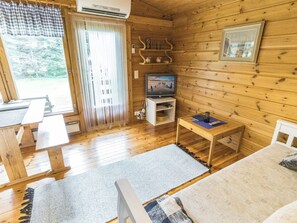 Interno di una baita in legno con televisione, un tavolo e una sedia.