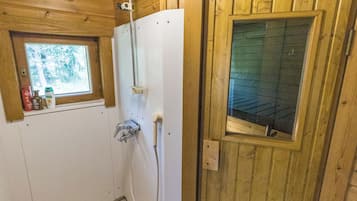 Un baño rústico con cabaña, con ducha, una ventana y una puerta.