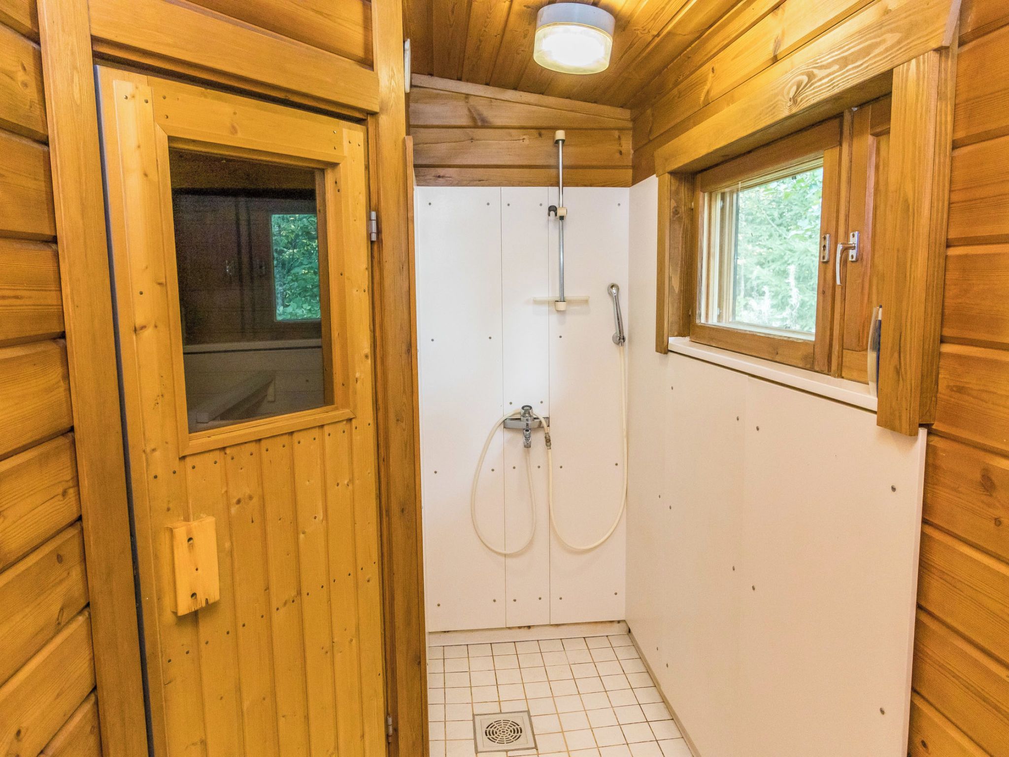 Una cabaña de madera con baño, paredes de madera y una ventana.