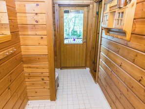 Un couloir intérieur aux murs en bois, avec une porte donnant sur un espace extérieur.
