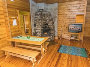 A cozy cabin interior with a stone fireplace, wooden furniture, and a television. - Vidnäs 6 by Interhome (Heinola)