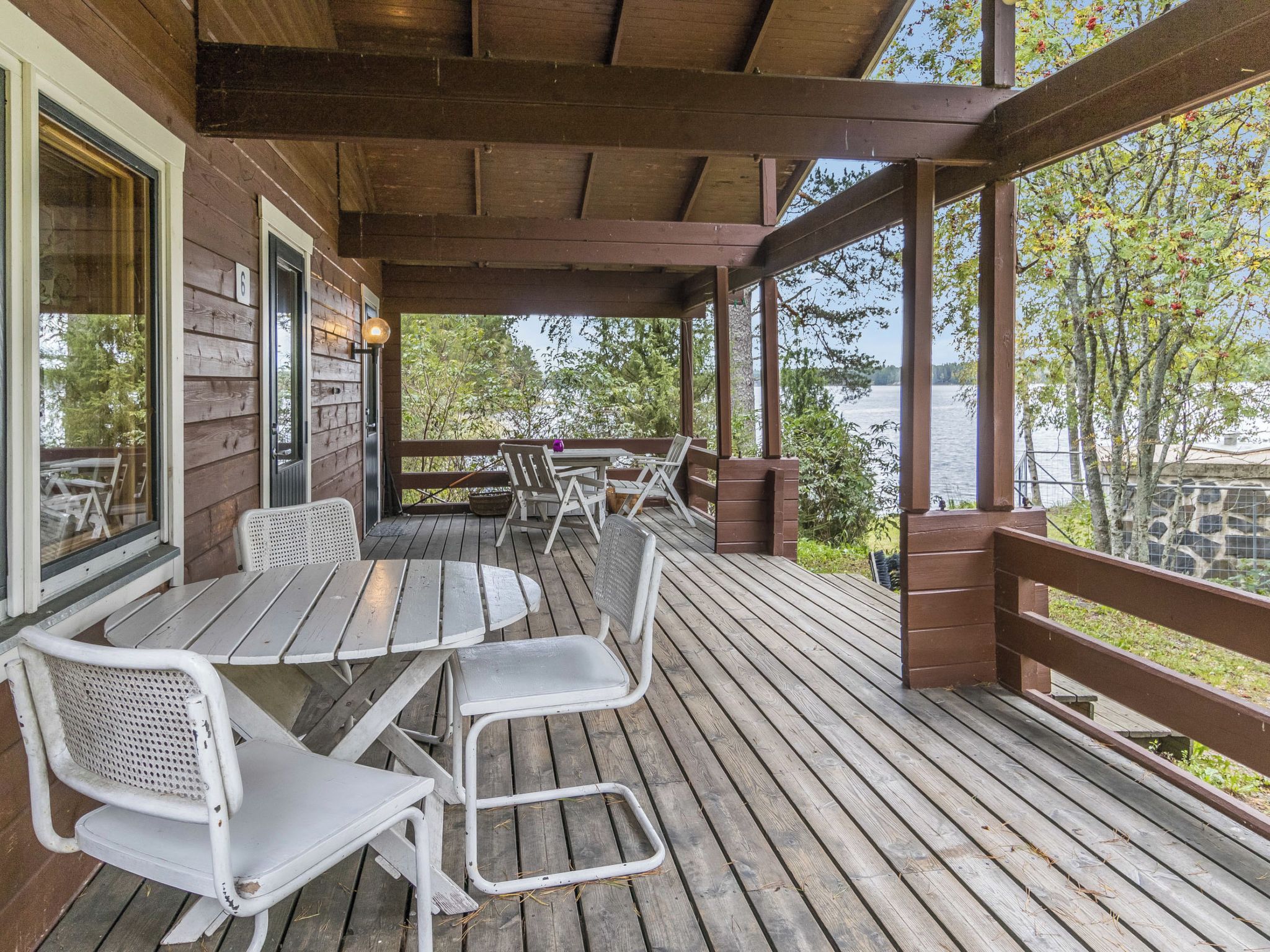 A wooden deck with outdoor seating and a view of a lake.