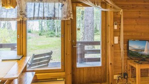 L’intérieur d’un chalet en bois, avec une table à manger, un banc et un téléviseur posé sur un meuble.