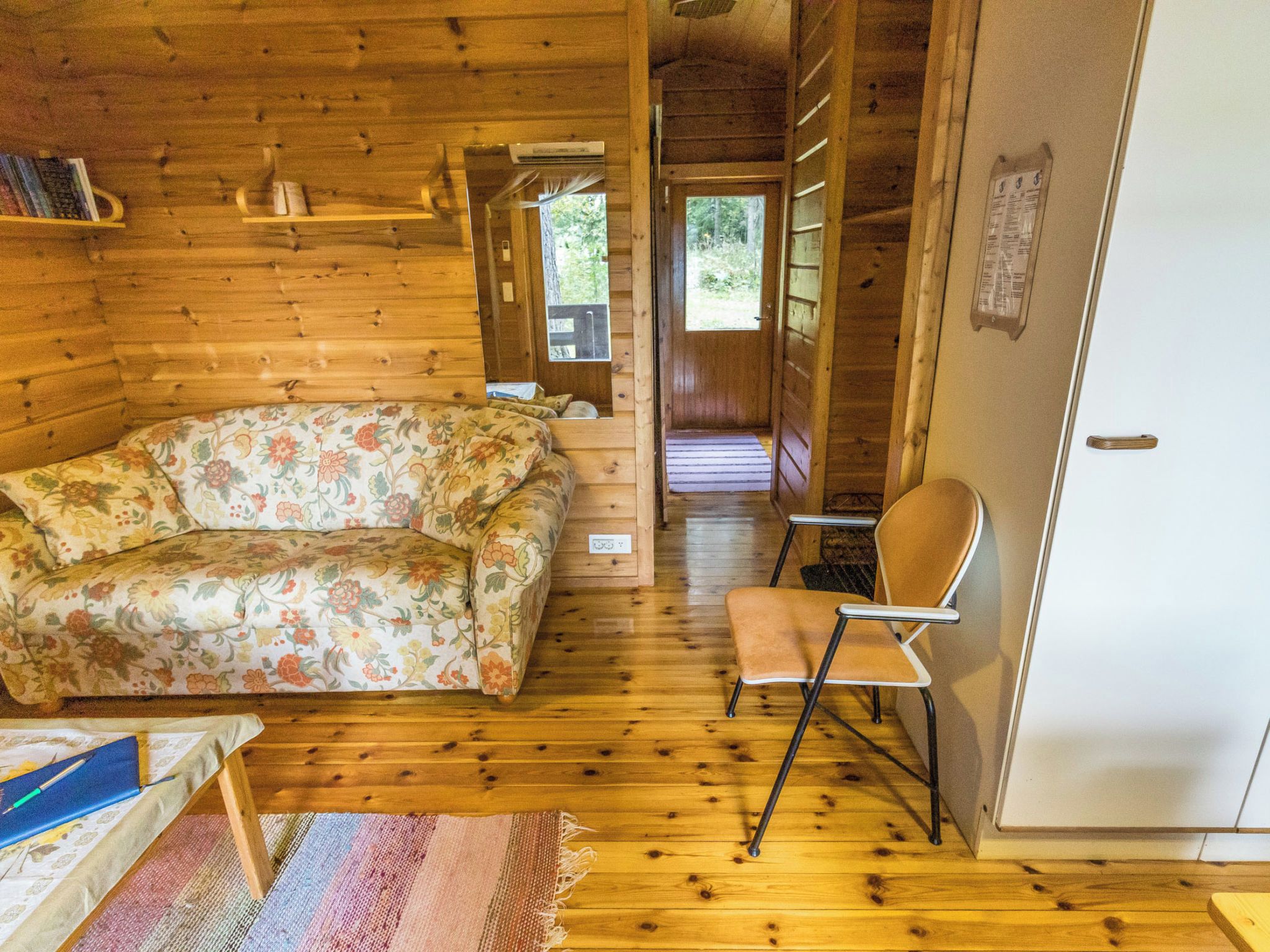 Ein Holzblockbau-Innenraum mit einer Couch, einem Sessel, einem kleinen Tisch und einem Kühlschrank.