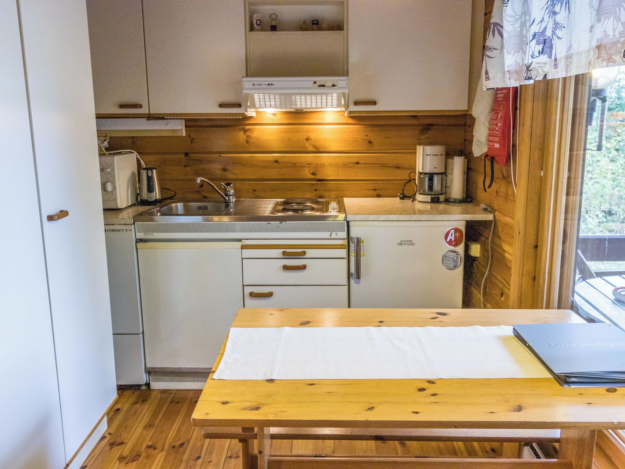 Una kitchenette compacta con pileta, estufa y cafetera.