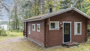 Une petite cabane à un seul étage, dotée d’un toit en pente, d’une porte d’entrée et de trois fenêtres.