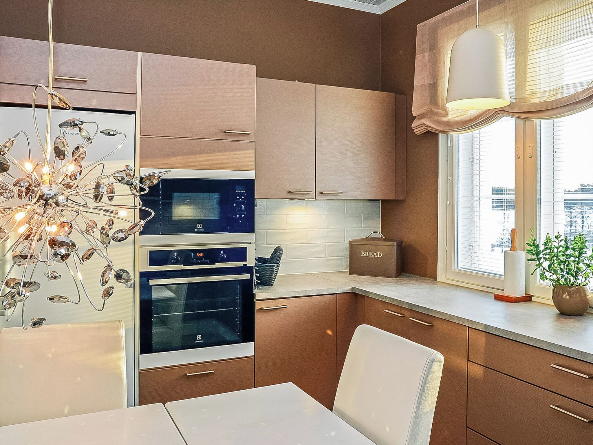 Eine moderne Küche mit Edelstahlgeräten, Holzschränken und einem Essbereich mit weißem Tisch und Stühlen.