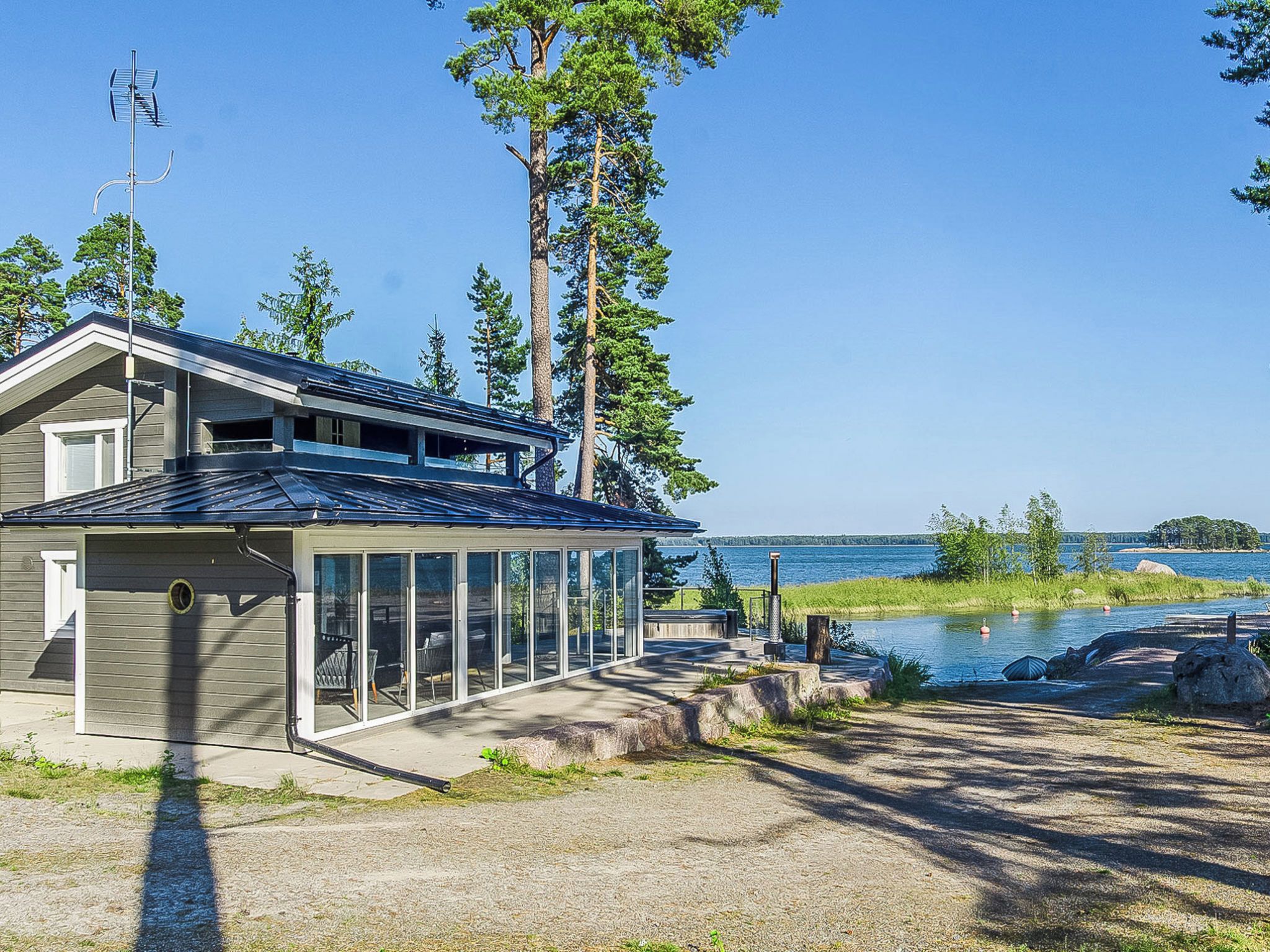 A modern house with a garage, a covered patio, and a view of a lake.