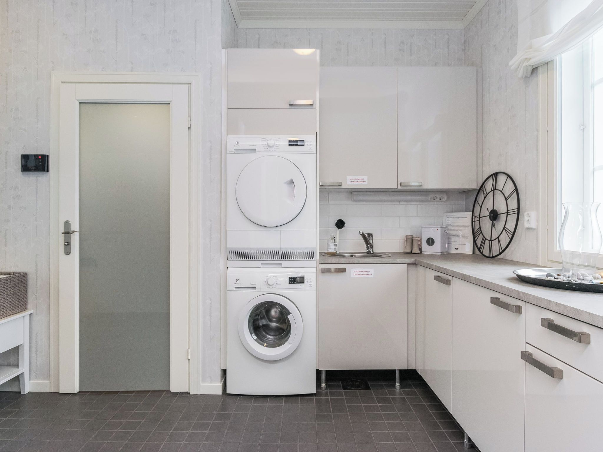 Une buanderie moderne équipée d’un lave-linge à chargement frontal, d’un sèche-linge et d’un espace de repassage intégré.