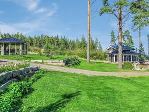 A well-maintained grassy area with a gazebo and a house with a blue roof.