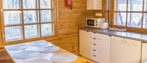 Una cocina con una mesa de madera, microondas y pileta.