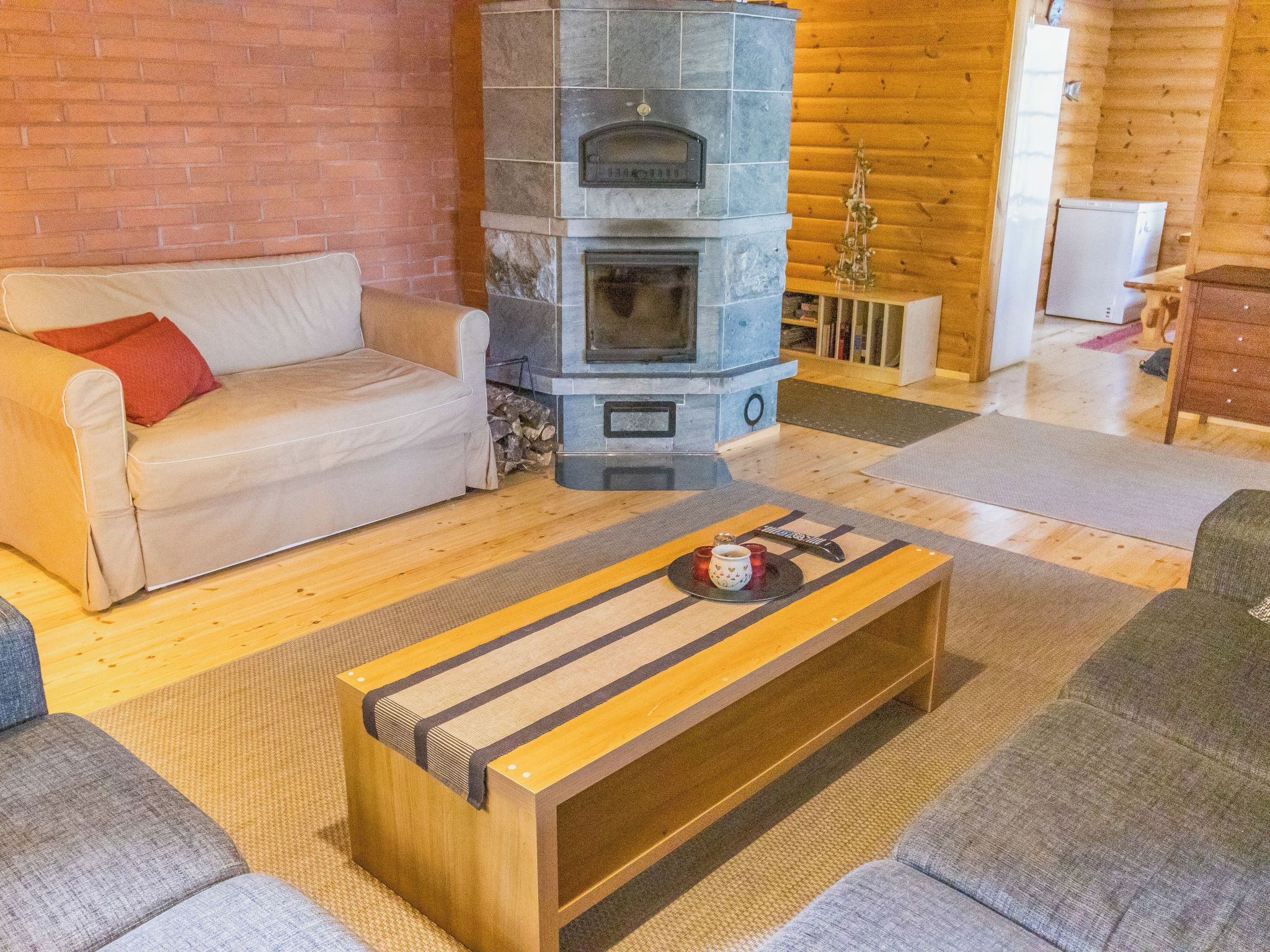 Un salon chaleureux avec une cheminée en pierre, un canapé, une table basse et un meuble en bois.