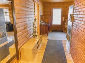 Interior de una cabaña de madera con un banco, una mesita y un espejo.