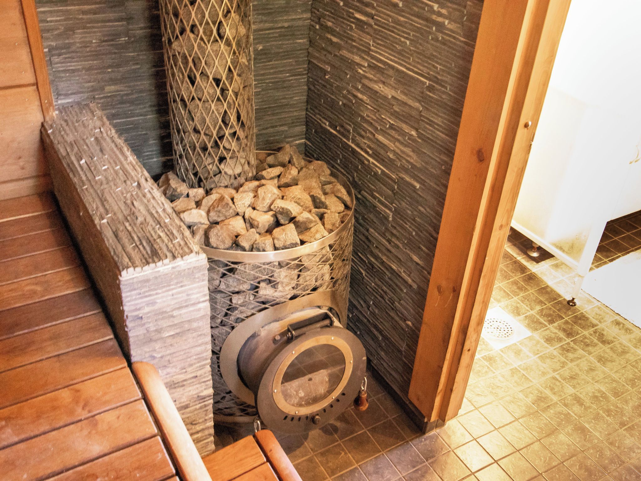 Un espacio pequeño y cerrado con un horno de piedra, un banco de madera y un suelo de baldosas.