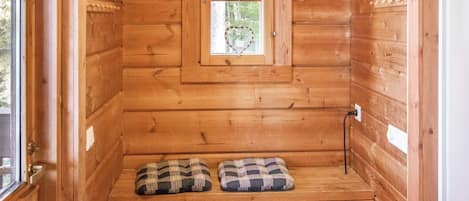 A wooden cabin with a window, a bench, and a door.