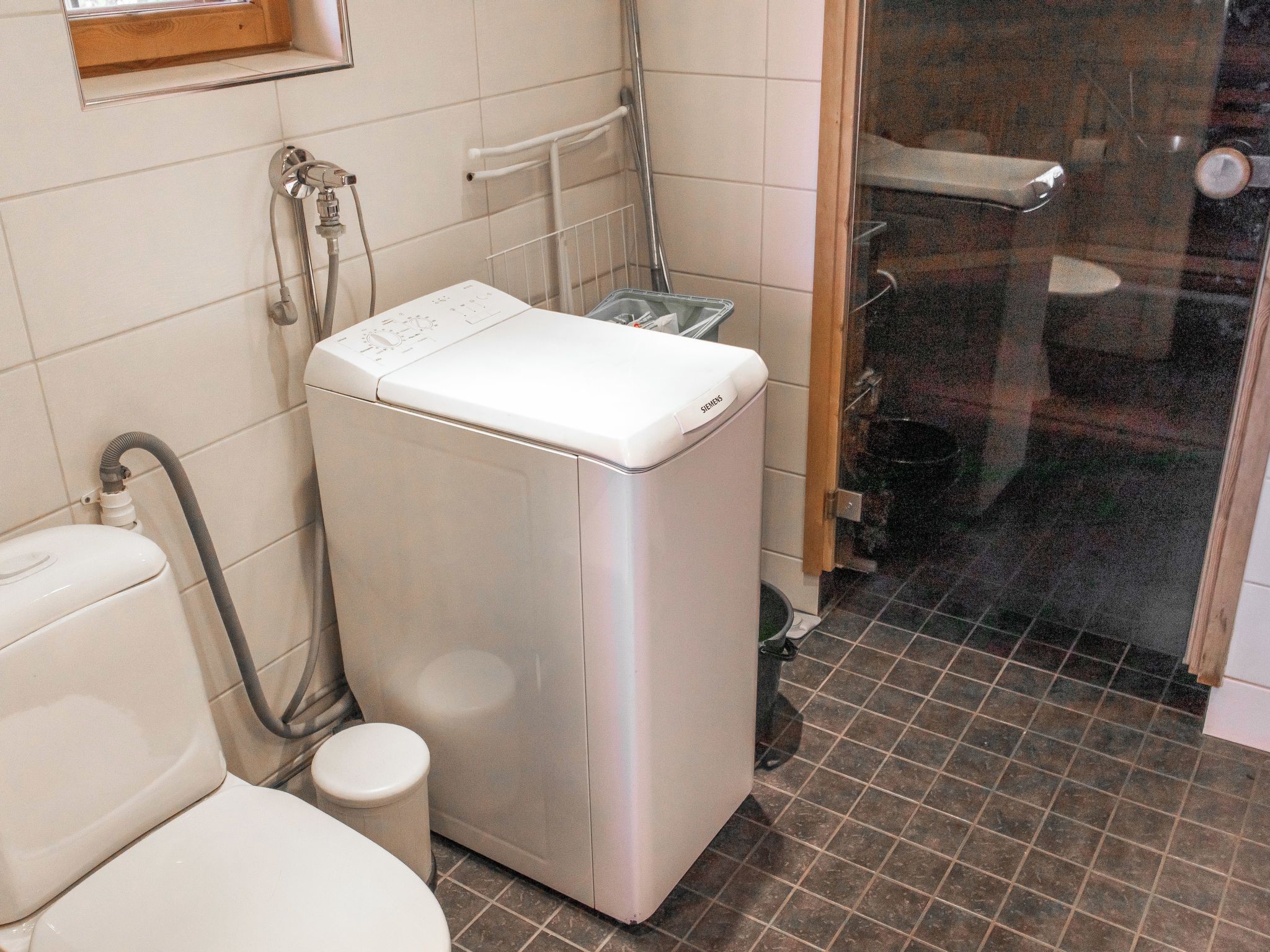 Een compacte, moderne badkamer met een wit toilet, een wasmachine en een douchehoek.