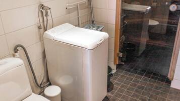 Een compacte, moderne badkamer met een wit toilet, een wasmachine en een douchehoek.