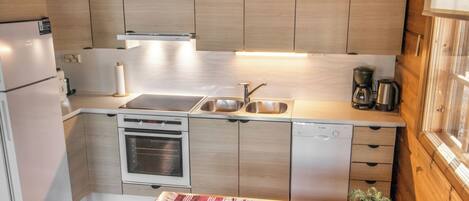 A compact kitchen with a built-in oven, a sink, and a coffee maker.