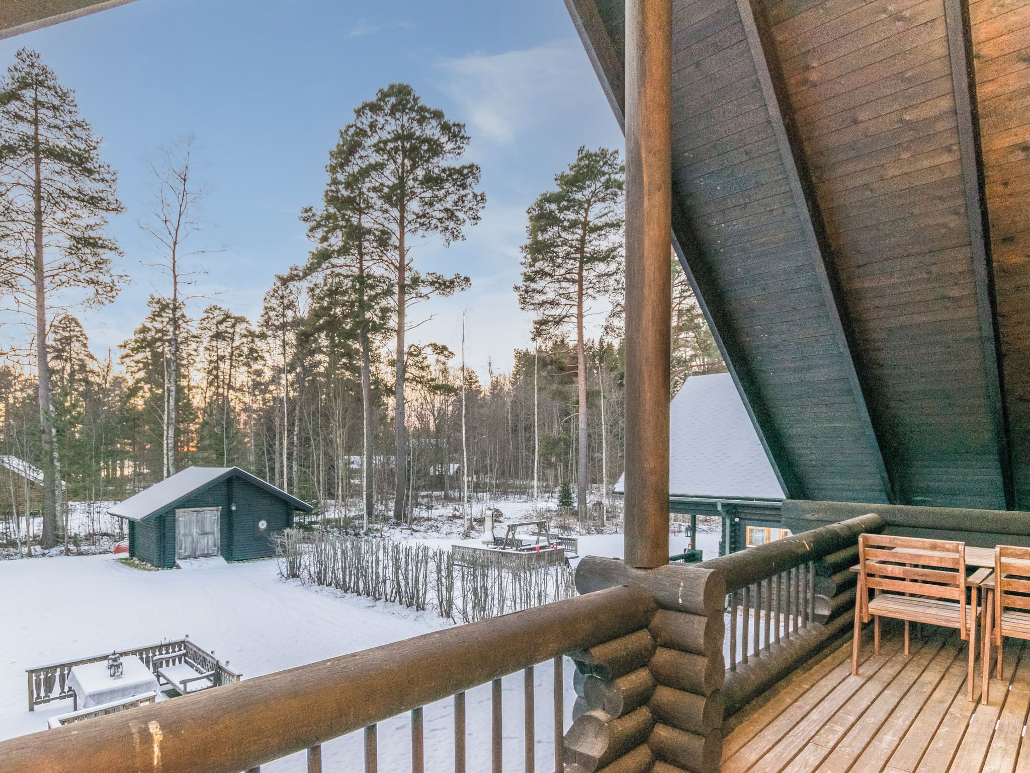 Eine Holterrasse mit Blick auf eine verschneite Landschaft und ein Blockhaus.