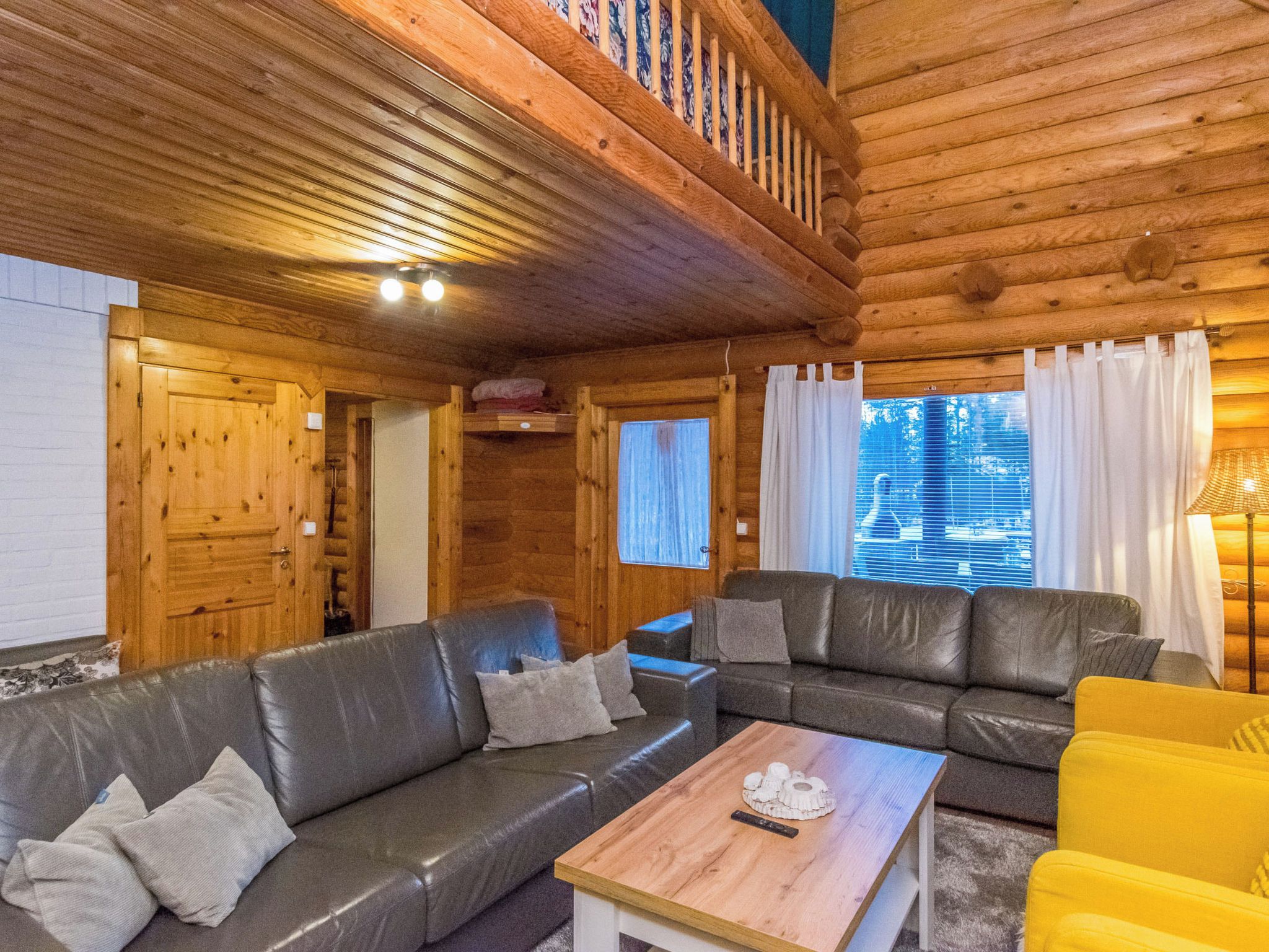 Un intérieur en bois avec un canapé, une table et une chaise jaune.