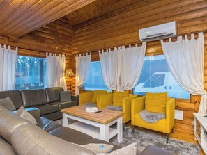 L’intérieur d’un chalet chaleureux, avec un canapé, des fauteuils jaunes, une table basse et une cheminée.