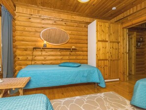 Une chambre aménagée dans un chalet en rondins, avec un lit, une petite table et un miroir au mur.