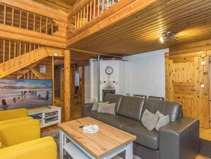 A wooden interior with a sofa, a coffee table, and a painting on the wall.