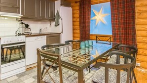 Een gezellige keuken met houten kasten, een fornuis en een eethoek met een glazen tafel en stoelen.