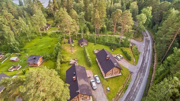 Luchtbeeld van een bebost gebied met verschillende hutten en een weg.
