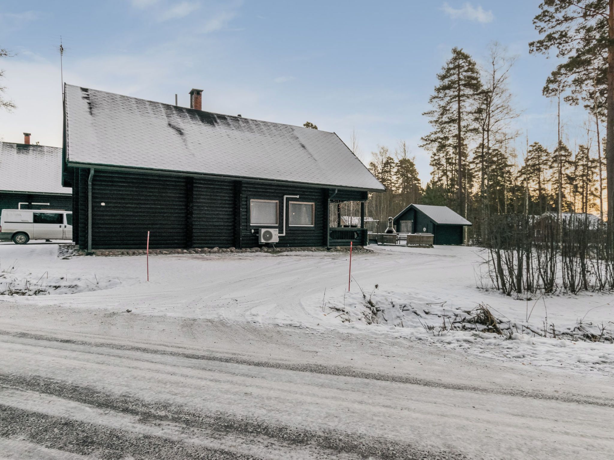 A snow-covered landscape with a black building featuring a large window and an air conditioning unit.