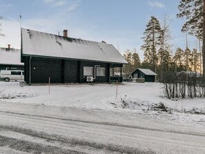 A snow-covered landscape with a black building featuring a large window and an air conditioning unit.
