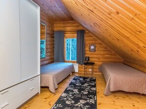 Une cabine équipée de deux lits, d’une armoire, d’une fenêtre avec des rideaux et d’un plafond en bois.