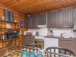 A compact kitchen with wooden cabinets, a microwave, a stove, and a dishwasher.