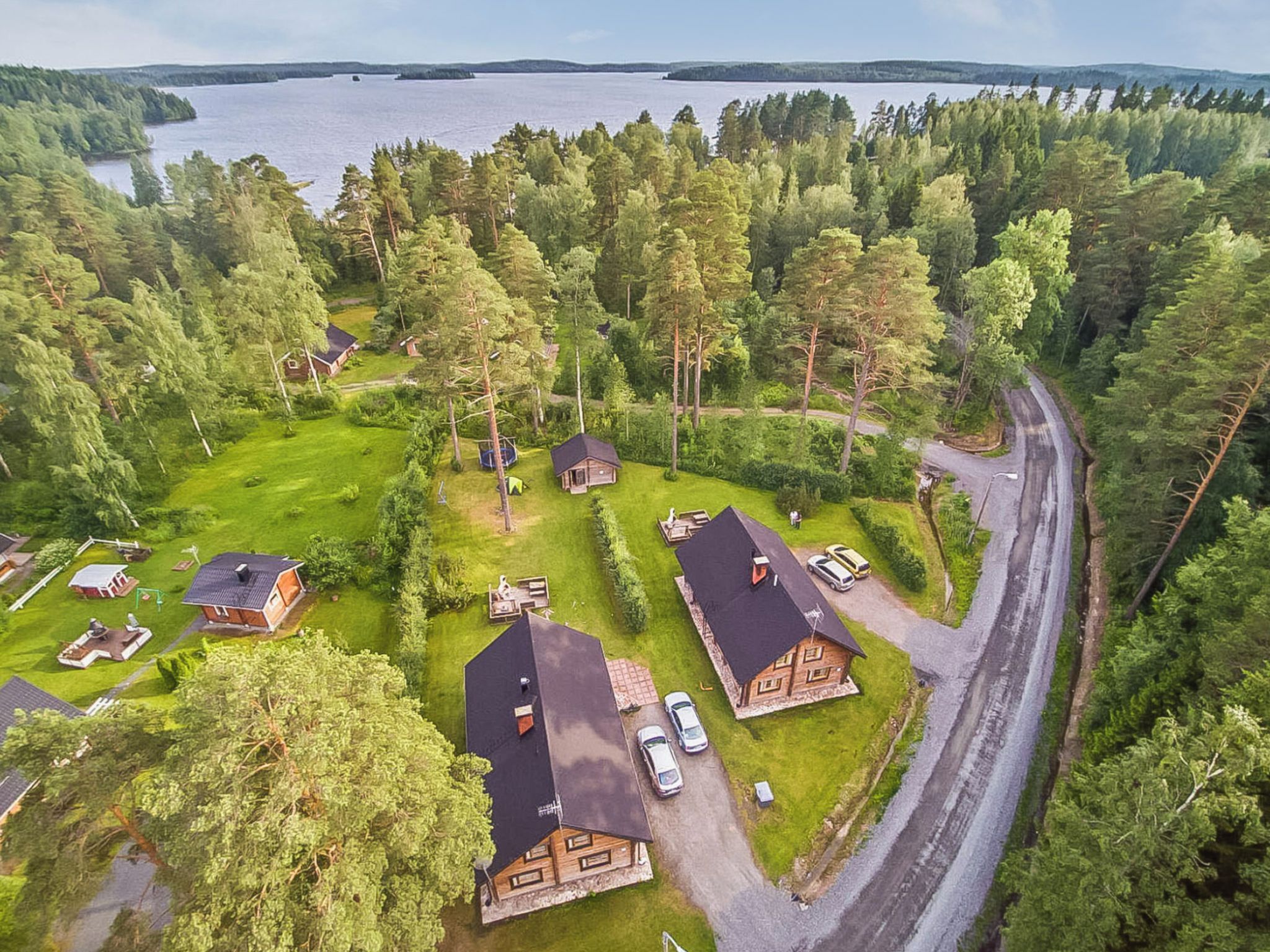 Un quartier résidentiel avec plusieurs maisons, une route et un lac en arrière-plan.