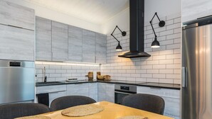 A modern kitchen with grey tiled walls, stainless steel appliances, and a wooden dining table with woven placemats.