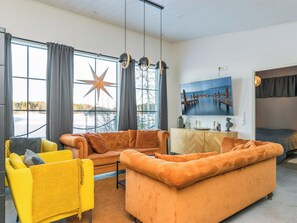 Un salon moderne avec un canapé, des fauteuils et une grande fenêtre agrémentée de rideaux.