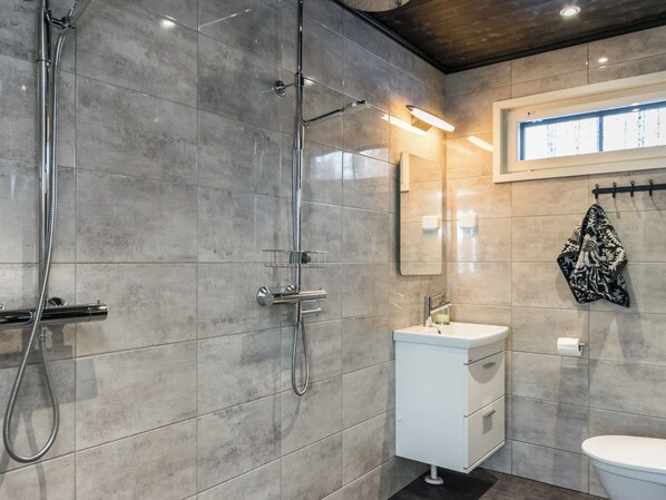 A modern bathroom with a shower, sink, and toilet.
