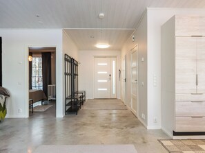 Un intérieur moderne avec un couloir menant à une porte, un banc et un porte-manteau.