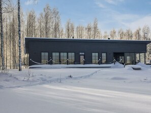 Un bâtiment moderne doté d’un toit plat, de grandes fenêtres et d’un sol recouvert de neige.
