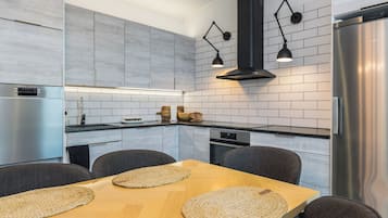 Eine moderne Küche mit einem Holzespeisetisch, schwarzen Pendelleuchten und Edelstahlgeräten.