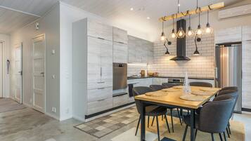 Una cocina moderna con zona de comedor, que incluye una mesa de madera, sillas e iluminación colgante.