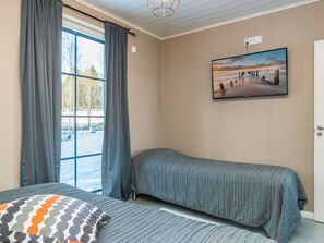 Une chambre avec deux lits, une fenêtre avec des rideaux, un tableau au mur et une porte.