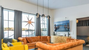 A modern living room with a large sofa, a yellow armchair, and a television on a wooden cabinet.