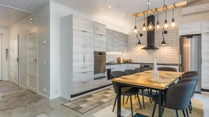A modern kitchen with a central island, built-in appliances, and a dining area with a wooden table and chairs.