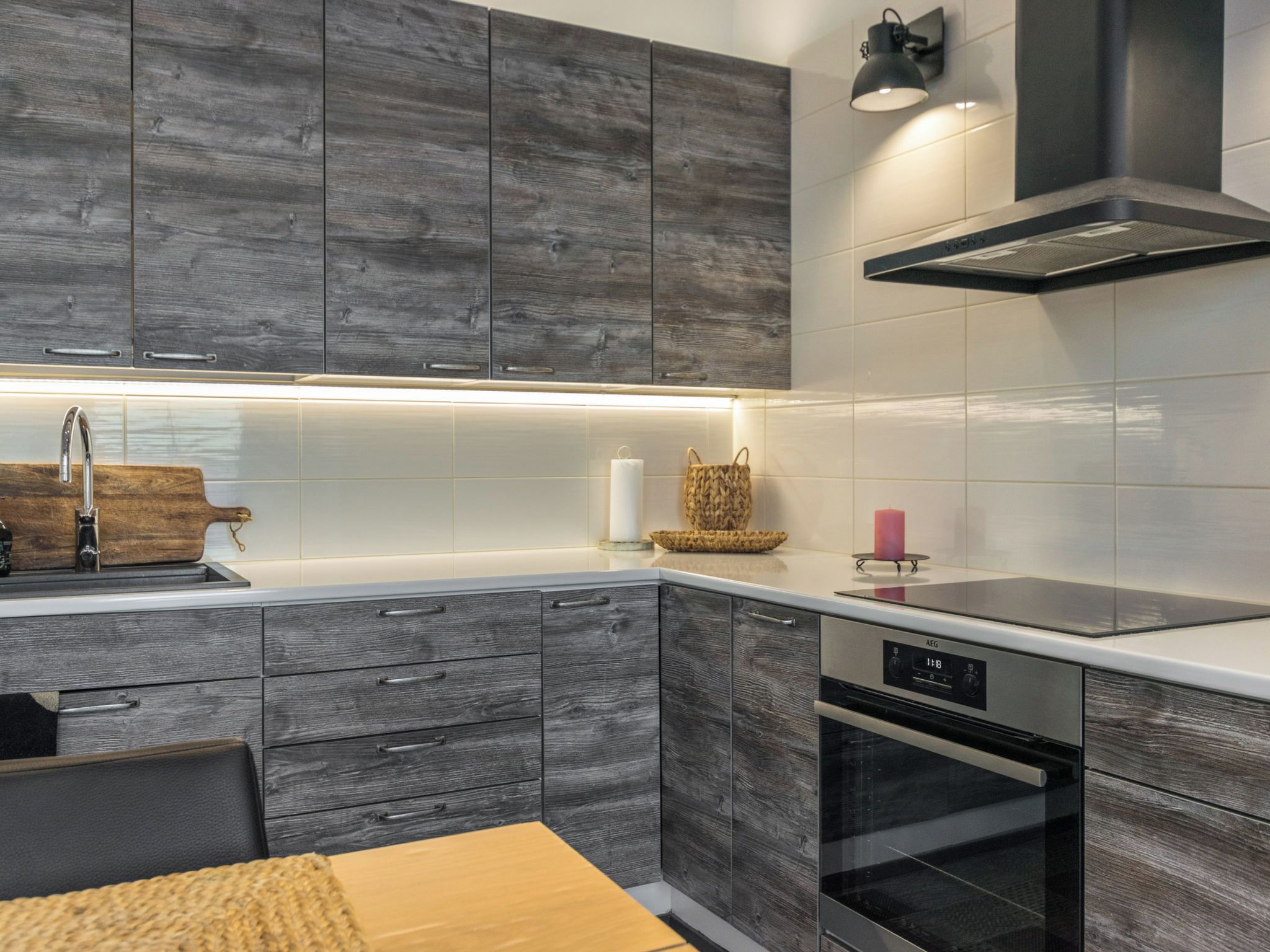 A modern kitchen with grey cabinetry, a stainless steel sink, and a built-in oven.