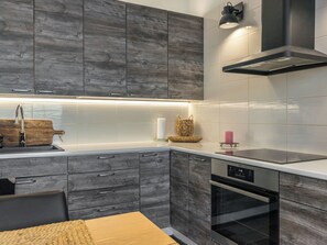 Una cocina moderna con armarios grises, un lavamanos de acero inoxidable y un horno empotrado.